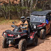 Single ATV and side by side ATV parked in sand