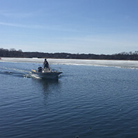 Ice Safety, early season boating Two people riding in a motorized boat on an icy lake.