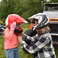 yound child putting a riding helmet with their mother