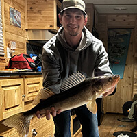 A person holding a walleye fish in a cabin.