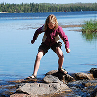 Girl playing on lakeshore rocks