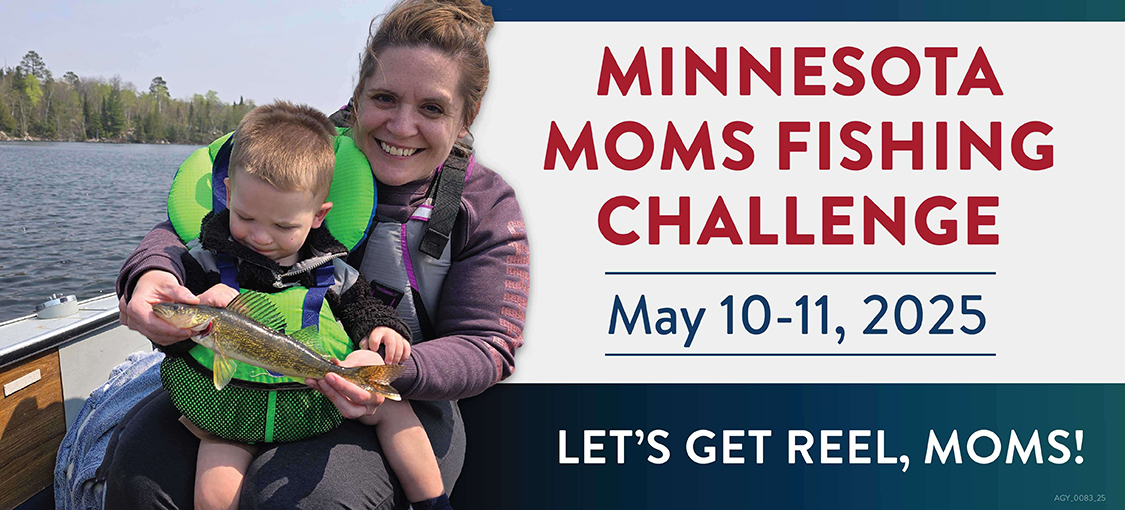 A mom holding a small child and fish, wearing life jackets in a boat on a lake.